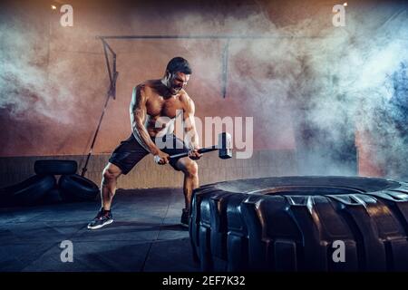 Entraînement sportif pour l'endurance, l'homme frappe grand marteau de pneu. Entraînement de concept. Banque D'Images