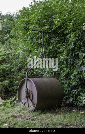 Tir vertical d'un vieux rouleau de cricket rustique avec des feuilles vertes en arrière-plan Banque D'Images