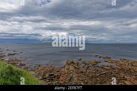 Vue sur l'île de stroma, une partie des Orkneys depuis la plage rocheuse de John OÕGroats en fin d'après-midi en mai. Banque D'Images