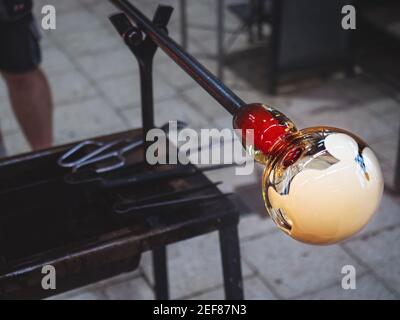 L'artiste souffleur de verre crée une couche de verre blanc sur un bol en verre transparent. Homme travaillant avec du verre chaud pour faire un morceau d'art en verre soufflé Banque D'Images