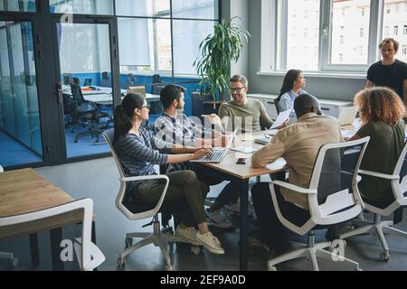 Jeune homme et jeune femme enthousiastes et concentrés assis à la table de bureau Banque D'Images