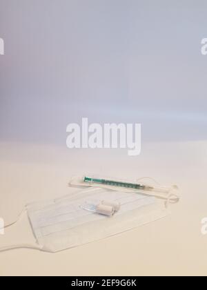 Vaccin en flacon, ampoules en verre et seringue avec masque de protection médical sur fond blanc, concept de vaccination globale Banque D'Images