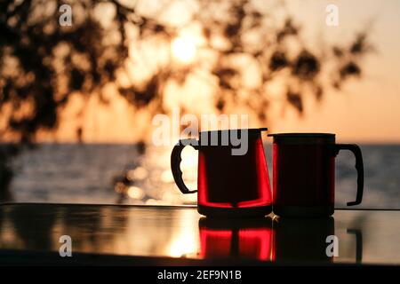 Couple coupe thermos avec coucher de soleil. Pique-nique pour les amoureux. Banque D'Images