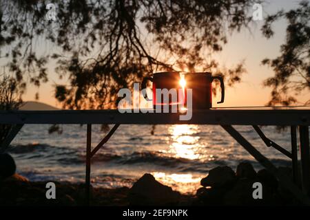 Couple coupe thermos avec coucher de soleil. Pique-nique pour les amoureux. Banque D'Images