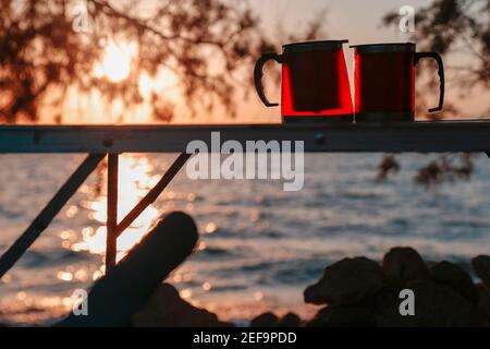 Couple coupe thermos avec coucher de soleil. Pique-nique pour les amoureux. Banque D'Images