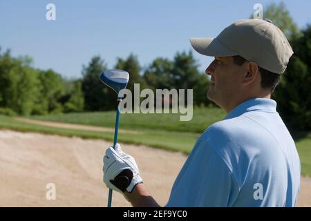 Close-up of a young man holding a golf club Banque D'Images