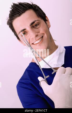 Portrait d'un chirurgien mâle tenant une ciseaux chirurgicaux et sourire Banque D'Images