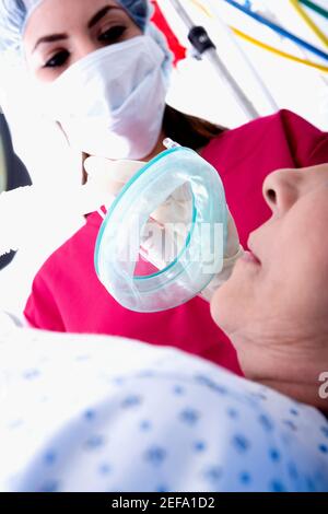 Vue à angle bas d'une femme chirurgien mettant un oxygène masque sur un patient Banque D'Images