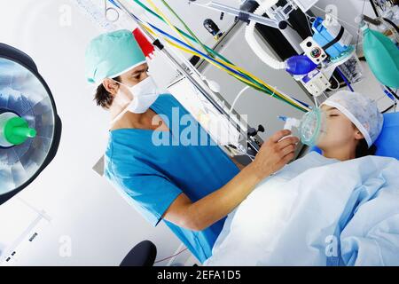 Chirurgien masculin mettant un masque d'oxygène sur la bouche de une patiente Banque D'Images