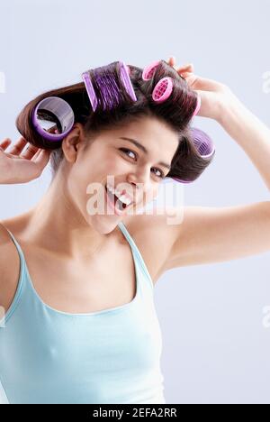 Portrait d'une jeune femme mettant des curlers dans ses cheveux Banque D'Images