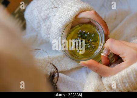 La jeune femme sur le canapé et avec du thé de sauge sur la main. Banque D'Images