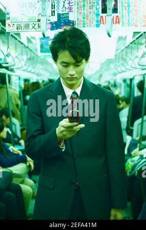 Homme adulte moyen exploitant un téléphone portable dans un train Banque D'Images