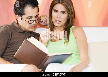 Jeune homme assis avec une jeune femme lisant un livre Banque D'Images