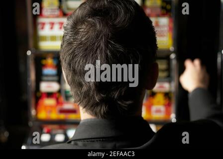 Vue arrière d'un adulte de taille moyenne jouant sur un machine à sous Banque D'Images