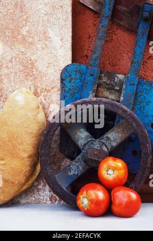 Gros plan de trois tomates près d'une roue et d'une pièce de pain Banque D'Images