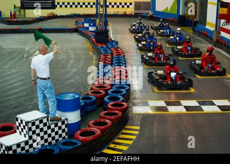 Vue en grand angle de la course Go cart à la ligne de départ avec un homme qui agite un drapeau Banque D'Images