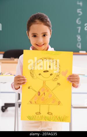 Portrait d'une écolière montrant son dessin et souriant Banque D'Images