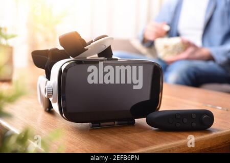 Casque de réalité virtuelle blanc et noir et manette de commande activée table en bois dans la salle de séjour Banque D'Images