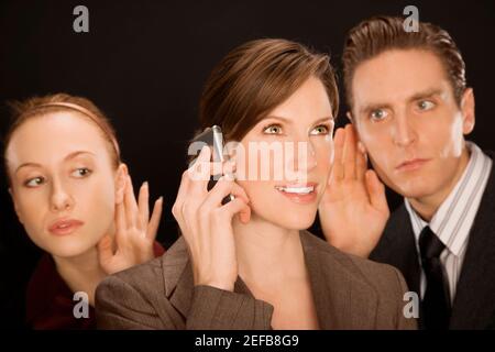 Femme d'affaires parlant sur un téléphone mobile avec deux cadres d'entreprise l'écouter Banque D'Images