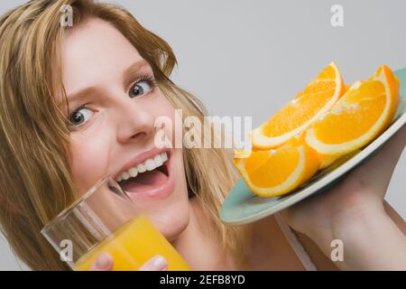 Portrait d'une adolescente portant une assiette d'oranges et un verre de jus d'orange Banque D'Images