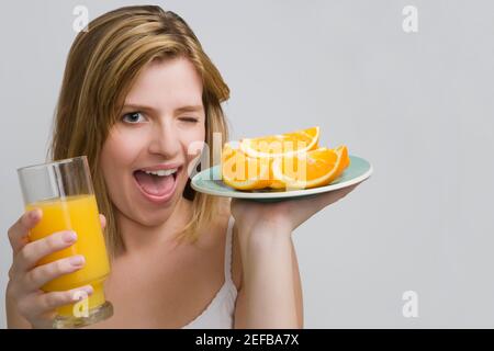 Portrait d'une adolescente portant une assiette d'oranges et un verre de jus d'orange Banque D'Images