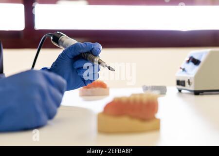 Gros plan des mains d'un technicien dentaire en train de faire de nouvelles Prothèses dentaires en laboratoire Banque D'Images