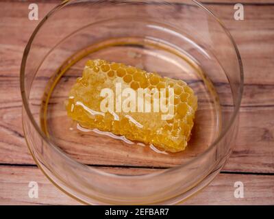 nid d'abeille doré dans un bol en verre sur fond de bois Banque D'Images