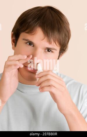Gros plan d'un jeune homme mettant des gouttes de spray nasal dedans son nez Banque D'Images