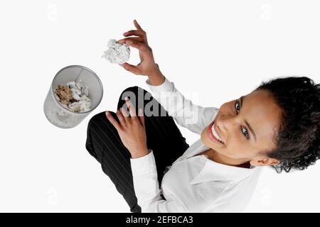 Vue en grand angle d'une femme d'affaires qui jette une feuille froissés de papier dans un panier à papier Banque D'Images