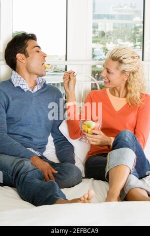 Gros plan d'une jeune femme qui nourrit de la salade à un jeune homme Banque D'Images