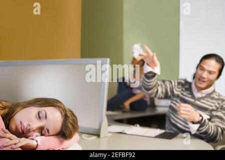 Gros plan d'une jeune femme qui fait la sieste et d'un jeune homme jeter un papier froissé sur elle Banque D'Images