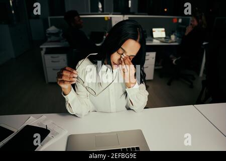 Une jeune femme d'affaires surtraitée et stressée se lasse des lunettes de vue de l'ordinateur travail sensation de mal de tête dans le bureau Banque D'Images