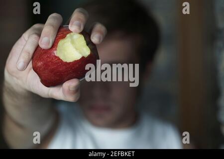 Gros plan d'une main humaine tenant une pomme partiellement mangée Banque D'Images