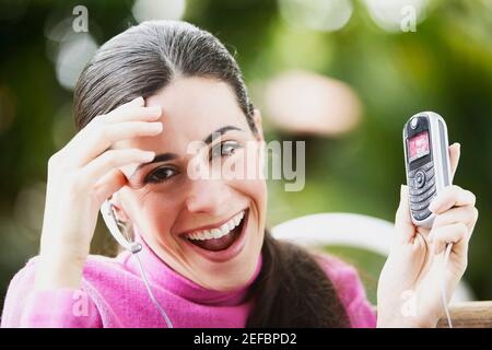 Portrait d'une jeune femme montrant un téléphone mobile et sourire Banque D'Images