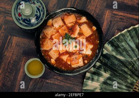 Matériau de la cuisine chinoise traditionnelle, tafu Mapo habillé avec une tasse de thé, et ventilateur de style chinois sur fond de bois. Banque D'Images