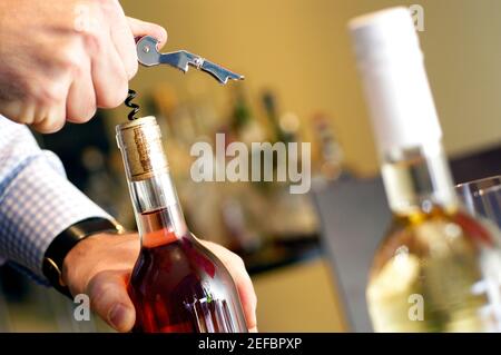 Gros plan d'un homme en dévissant le liège d'une bouteille de vin Banque D'Images