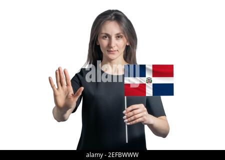 Bonne jeune femme blanche tenant le drapeau de la République dominicaine et avec un visage sérieux montre un signe d'arrêt de main isolé sur un fond blanc. Banque D'Images