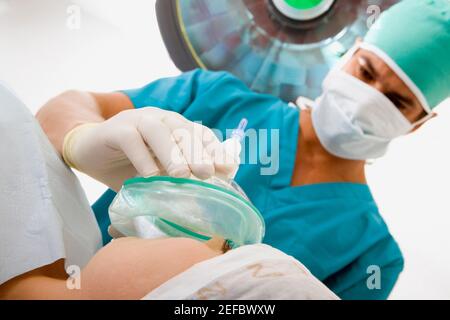 Chirurgien masculin mettant un masque à oxygène sur une patiente Banque D'Images