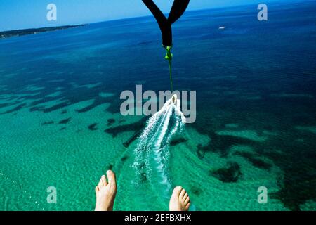 Les pieds d'un homme sont vus comme il parapente au-dessus de la plage de Negril, en Jamaïque Banque D'Images