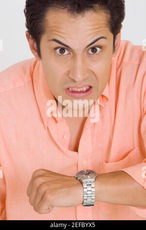 Portrait d'un jeune homme faisant un visage après vérification le temps sur sa montre-bracelet Banque D'Images