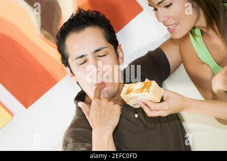 Un jeune homme léchant son doigt avec une jeune femme tenant une pâtisserie Banque D'Images