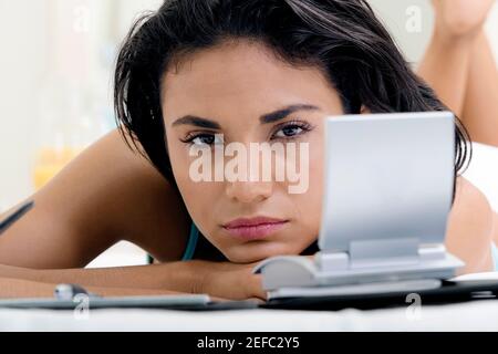 Portrait d'une jeune femme allongé sur un lit avant d'un organiseur personnel Banque D'Images
