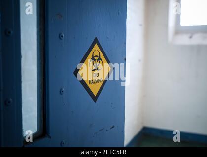 Avertissement danger autocollant de danger biologique sur la porte ouverte bleue de la cellule de prison la lumière du soleil sous la fenêtre de haute sécurité a fait tomber l'immigration de prison Centre de détention Angleterre Banque D'Images