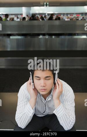 Homme d'affaires portant des écouteurs et écoutant de la musique dans un aéroport Banque D'Images