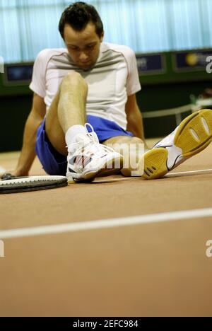 Homme adulte de taille moyenne assis sur un court de tennis Banque D'Images