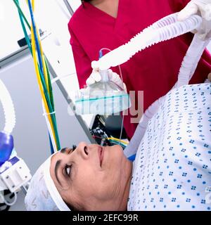 Femme chirurgien mettant un masque d'oxygène sur une patiente face Banque D'Images