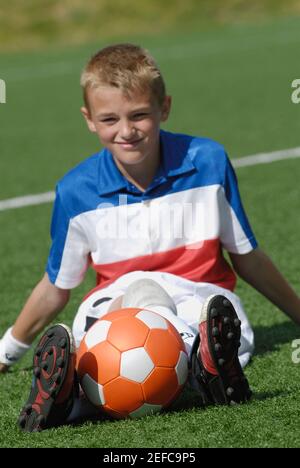 Portrait d'un joueur de football assis avec un ballon de football Banque D'Images