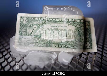 Gros plan d'une facture d'un dollar enroulée autour d'un cube de glace Banque D'Images