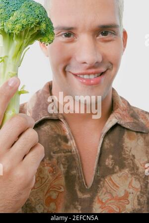 Portrait d'un jeune homme tenant le brocoli Banque D'Images