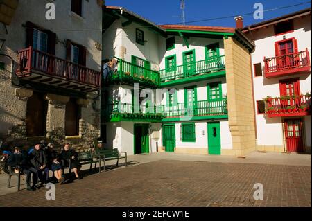 Quatre personnes assises sur un banc dans une cour, Espagne Banque D'Images